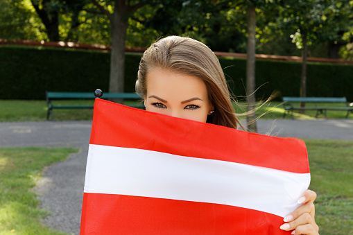 Young woman holding austrian flag in park