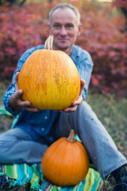 istock Man stretches out to the camera a huge pumpkin 861348866