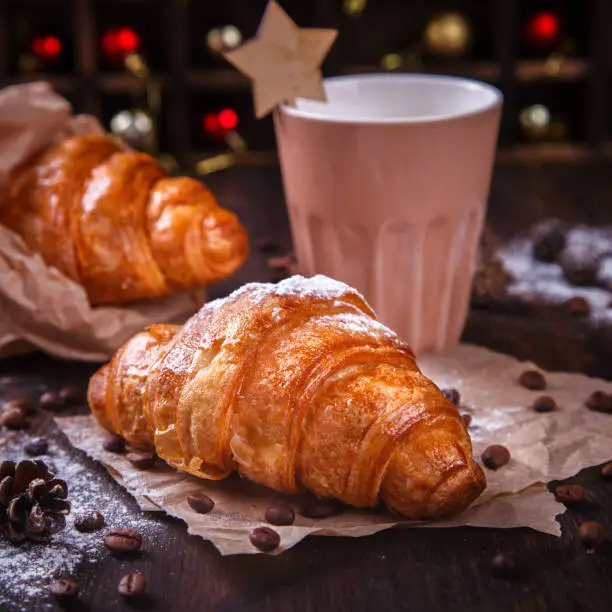 Christmas or New Year pastries,Croissant with a warming drink,coffee.Winter Holidays Concept.Holiday Decorations. top view.Vintage style. selective focus.