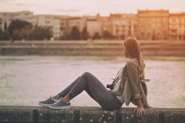 istock Woman with camera and backpack  sitting at the riverbank 861380156