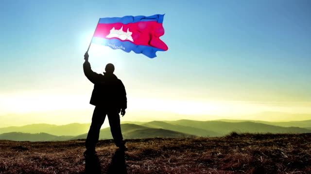Successful silhouette man winner waving Cambodia flag on top of the mountain peak Cinemagraph LOOP background