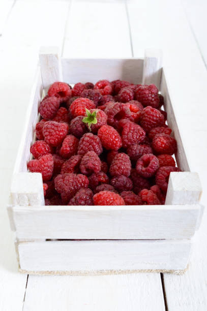 istock Fresh juicy pink raspberry in a wooden box on a white background. Harvest. 861463996
