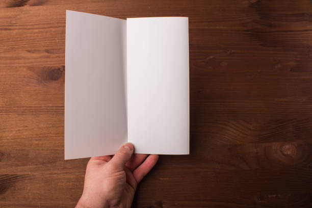 istock Blank tri fold brochure in hand on wooden background to replace your design or message 861489742