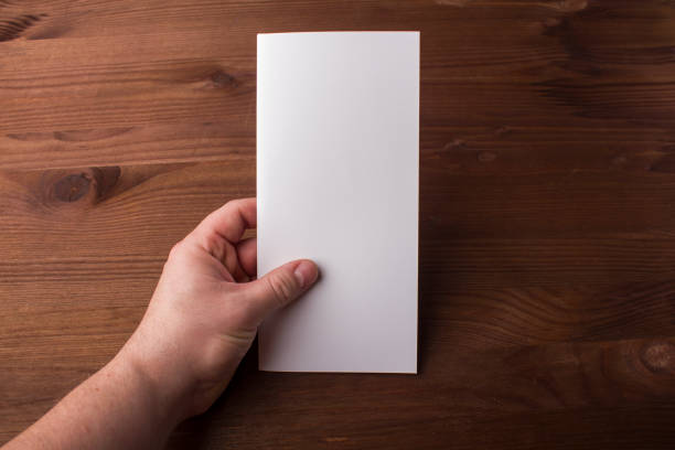 istock Blank tri fold brochure in hand on wooden background to replace your design or message 861489744