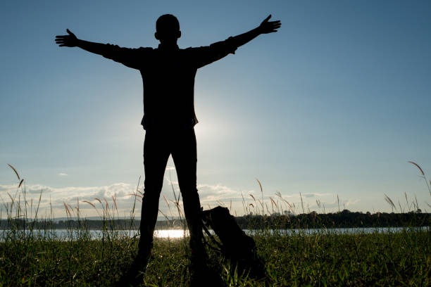 Man standing near the river with his arms wide open