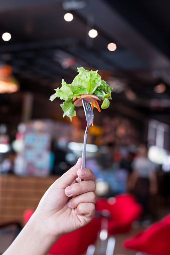 Woman hand holding Salad vegetables on fork.