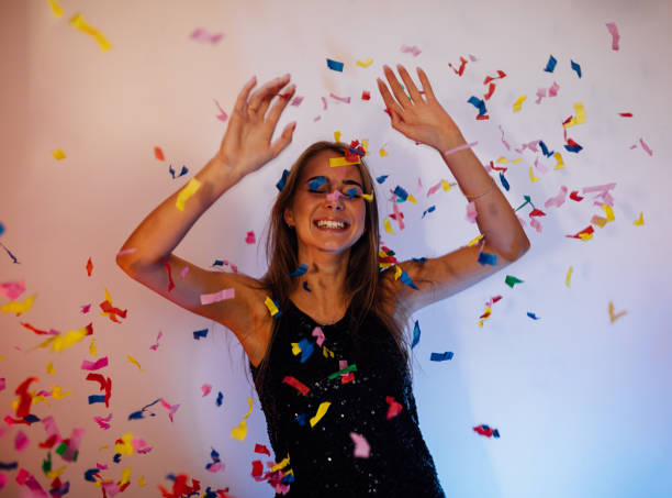 istock Young happy woman raised her hands, standing indoors under confetti 861517664