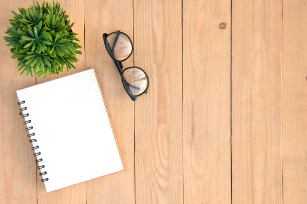 istock Copy space blank white book open and eyeglasses and small tree over wooden table, top angle view 861517694