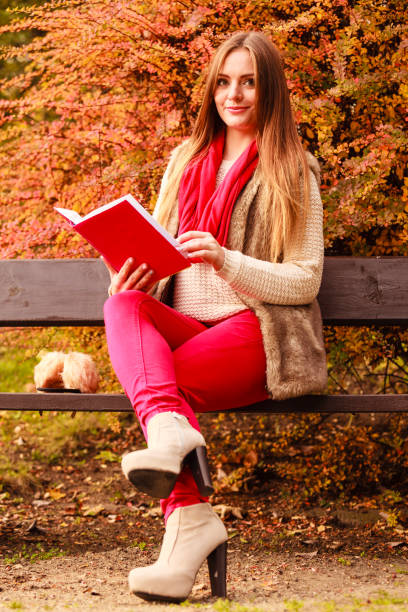 istock Woman relaxing in autumnal park reading book 861545768