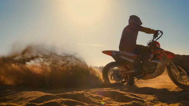 Photo of Professional Motocross FMX Motorcycle Rider Drives in Circles on the Off-Road Deserted Quarry.