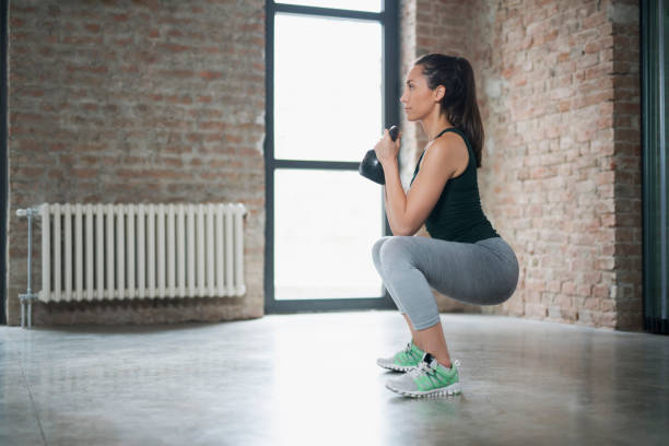 Giving Up Is Simply Not An Option Side view of a beautiful young woman doing kettlebell goblet squats. sportsman professional sport side view horizontal stock pictures, royalty-free photos & images