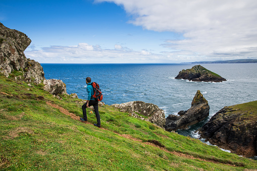 Solo traveler exploring the rocky coastline in Cornwall, UK