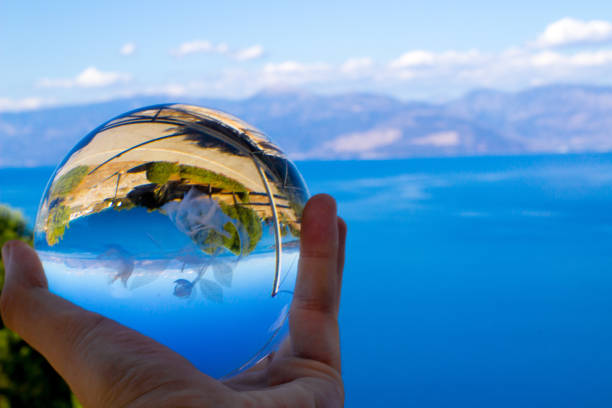 reflet d’un paysage coloré par une boule de cristal - transparent crystal crystal ball human hand photos et images de collection