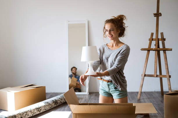 Young couple moving in new house, unpacking boxes.