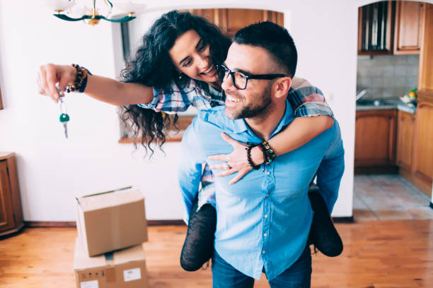 Young couple holding keys of new apartment Young couple holding the keys for their new home. key package stock pictures, royalty-free photos & images
