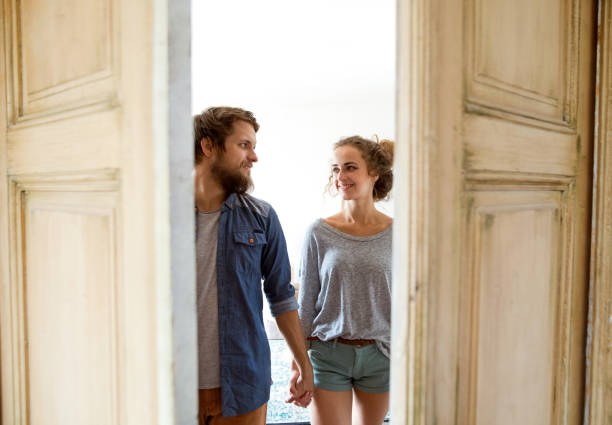 pareja se mueve en la casa nueva, entrando por la puerta. - couple old fashioned hipster holding hands fotografías e imágenes de stock