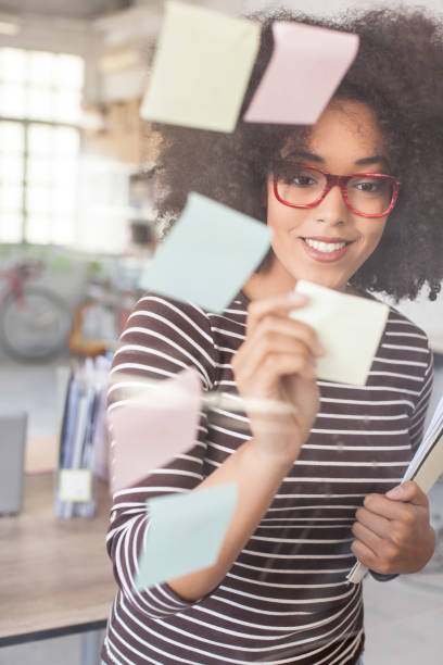 istock Smiling african woman writing adhesive notes at workplace 861619006