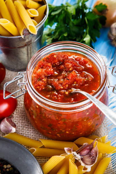 istock Tomato sauce and uncooked pasta on wooden background 861641314
