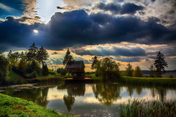 house by the lake on a background of colorful evening sky at sunset, beauty of nature, Belarus