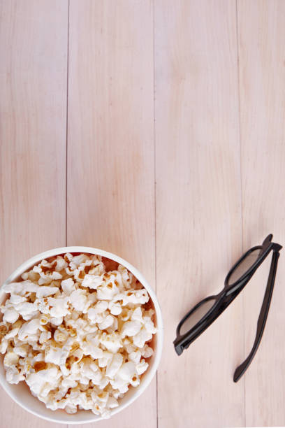 Bowl with popcorn and 3D glasses on a wooden background top view