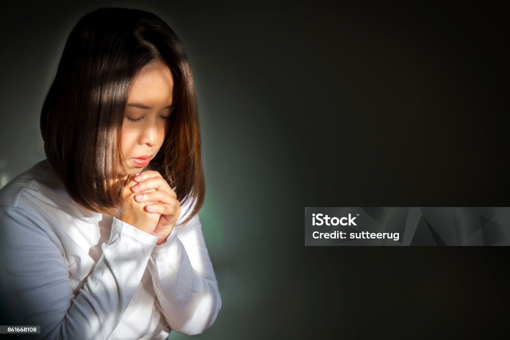 Middle adult Asian woman sitting and praying for blessings. With dark vignette and light color effect look like aura from inner. Middle adult Asian woman sitting and praying for blessings. According to religious beliefs. With light effect and dark vignette. 30-39 Years Stock Photo