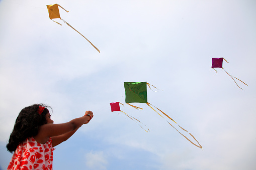Kite in a blue sky. Rainbow Delta Kite flying among the clouds. Happy growing years moment. Outdoor time spending. Aspirations, target, inspiration concept. Freedom and summer holiday. Childhood dream
