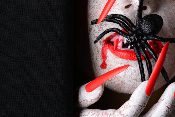 Scary fanged halloween vampire eating a spider A scary fanged halloween vampire with sharp red claws eating a spider against a black background. fanged stock pictures, royalty-free photos & images