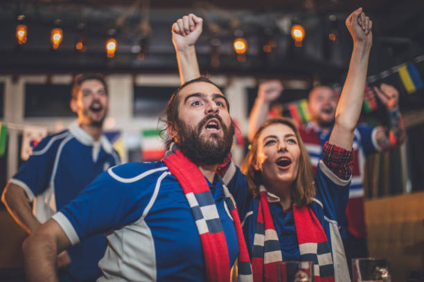 Friends cheering Group of close friends watching a game at the bar and cheering for their team. fan enthusiast stock pictures, royalty-free photos & images