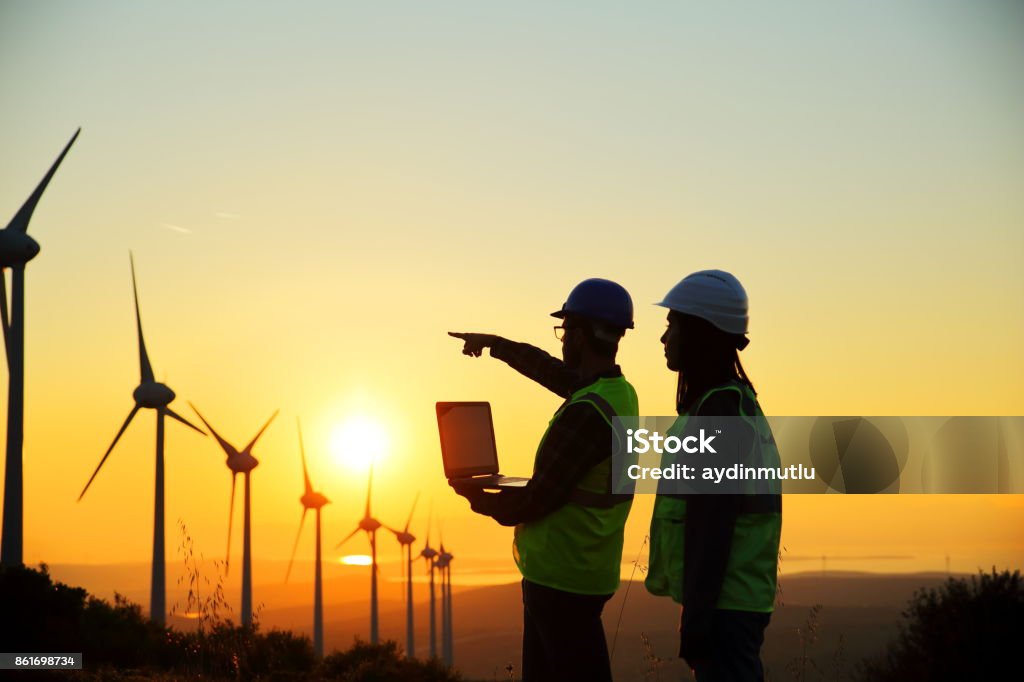 Windmills and Workers In Silhouette Stock Photo