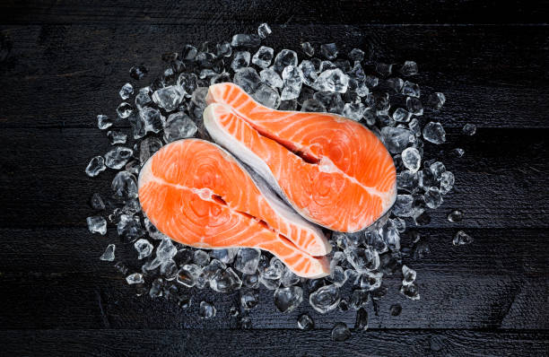 istock Salmon steak on ice on black wooden table top view 861705432