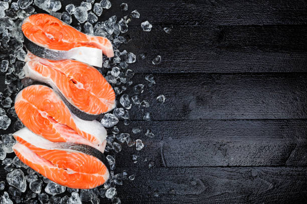 istock Salmon steaks on ice on black wooden table top view. Copy space 861705500