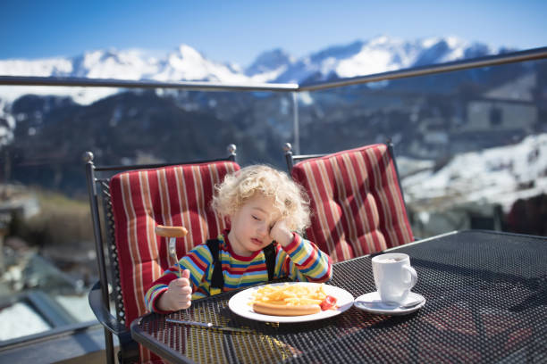 niño comiendo apres almuerzo de esquí. diversión de la nieve de invierno para niños. - apres ski ski restaurant mountain fotografías e imágenes de stock