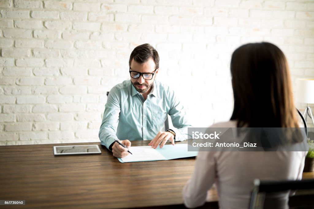 Man interviewing a woman for a job Male recruiter looking at a woman's resume during an interview for a new job position Occupation Stock Photo