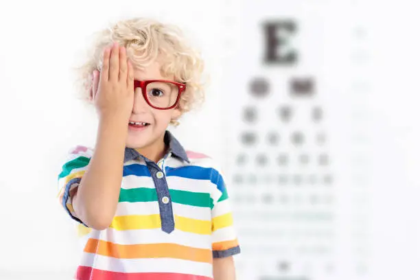 Child at eye sight test. Little kid selecting glasses at optician store. Eyesight measurement for school kids. Eye wear for children. Doctor performing eye check. Boy with spectacles at letter chart.