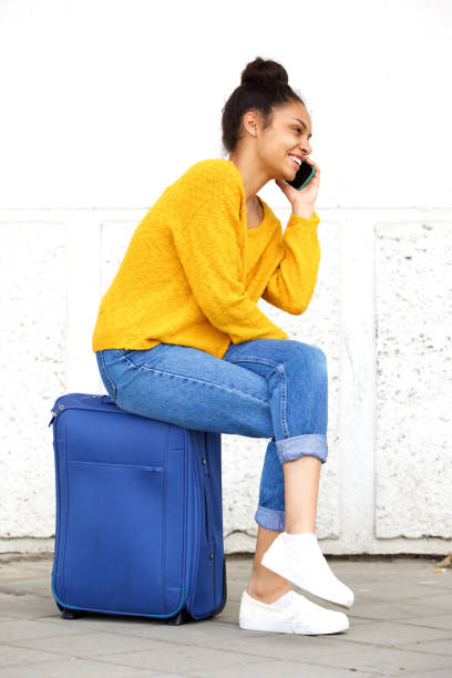 istock Woman sitting on suitcase and talking on cellphone 861759200