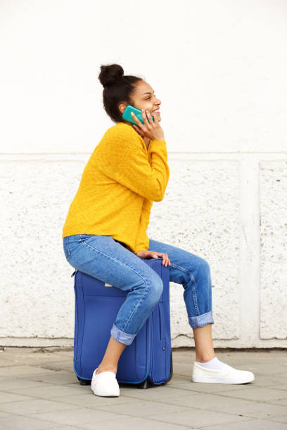 istock African woman sitting on suitcase and making phone call 861759328