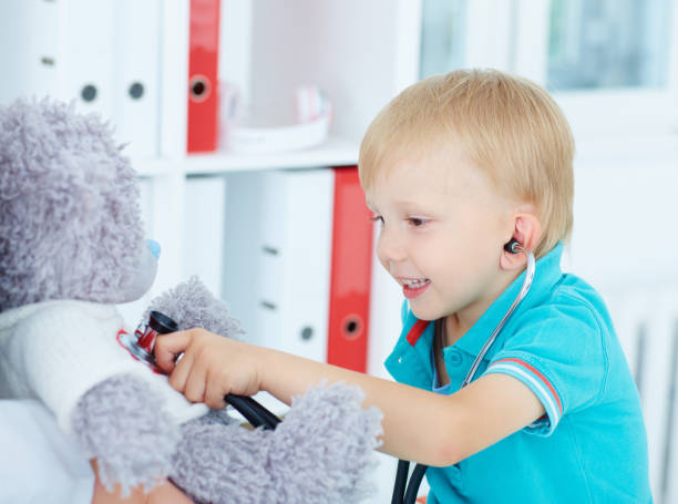 istock boy doctor examining teddy bear. 861770120