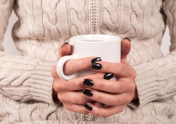 istock Female hands with black nails and sweater holding cup of tea 861773268