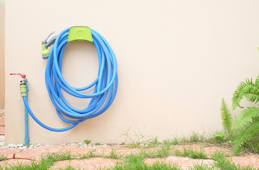 watering hose hanging on the wall in garden