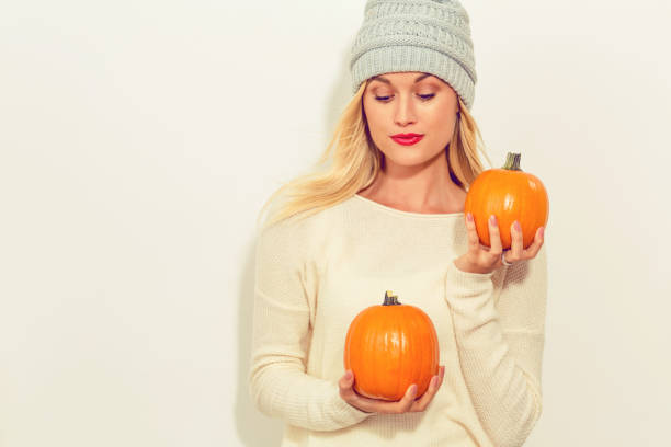 Young blonde woman holding pumpkins for halloween