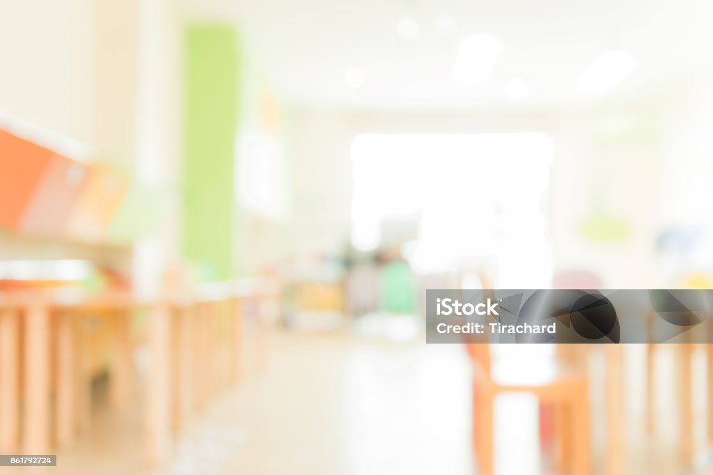 School classroom in blur background without young student; Blurry view of elementary class room no kid or teacher with chairs and tables in campus. Vintage effect style pictures. Backgrounds Stock Photo