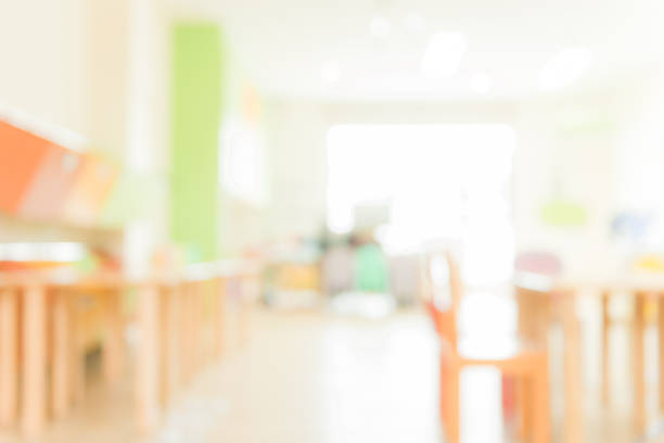 School classroom in blur background without young student; Blurry view of elementary class room no kid or teacher with chairs and tables in campus. Vintage effect style pictures. stock photo