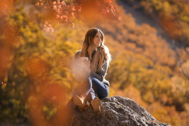 istock Woman sitting on rock drinking coffee 861794848
