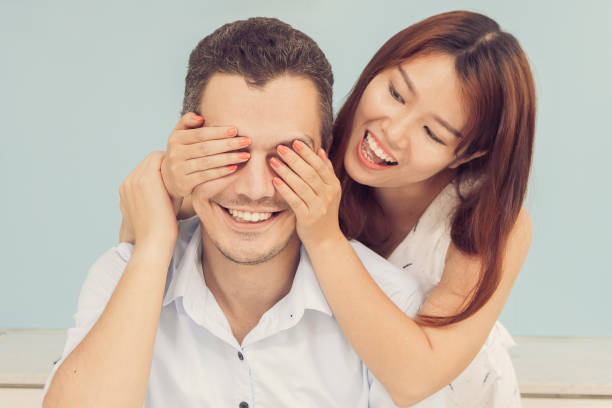istock Smiling Woman Covering Husband Eyes in Kitchen 861814064