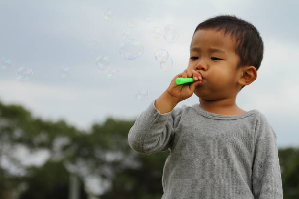 Japanese boy playing with bubble (3 years old) on the grass