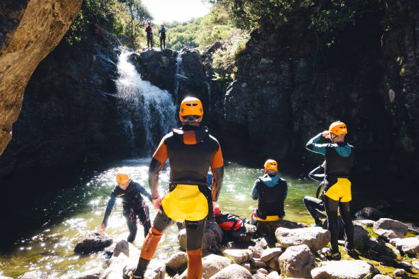 Canyoning On Madeira Island Madeira, Portugal - June 30, 2016: Tourists practicing canyoneering in canyon near Levada das 25 Fontes e Risco in Madeira Island. Group waiting for two members to jump into the water. neoprene photos stock pictures, royalty-free photos & images