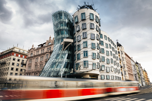 Prague, Czech Republic - February 05, 2013: Moving red tram in front of Dancing house in Prague. The building was designed by the architect Vlado Milunić in cooperation with Frank Gehry. It was designed in 1992 and completed in 1996.