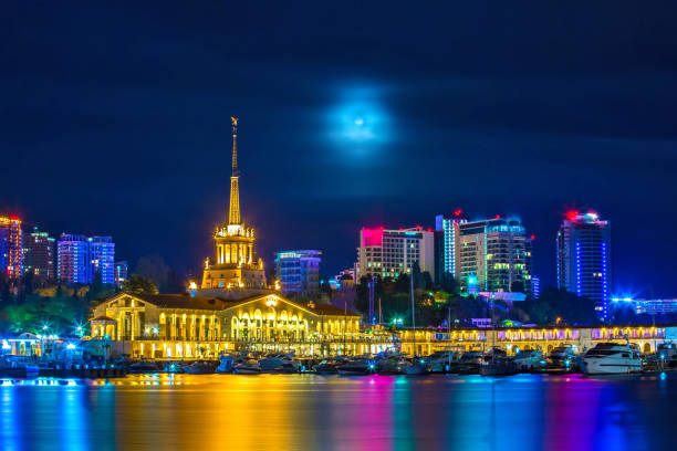 Mystical Sochi, Central Marine Station, Welcome to Russia 2018. The building of the city seaport against the background of high-rise buildings at night, with the moonlight hidden behind the clouds. sochi stock pictures, royalty-free photos & images