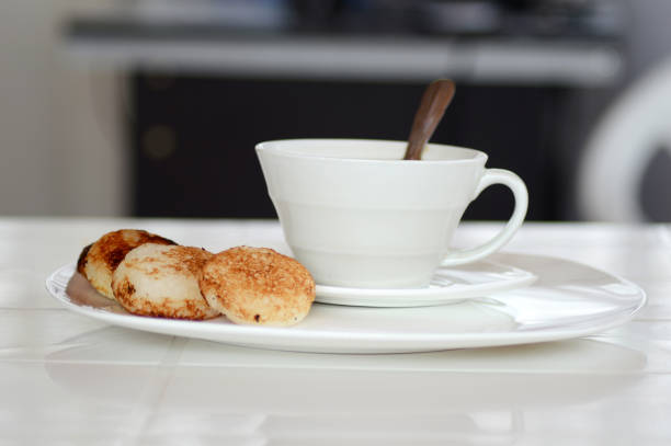 Two cups of coffee or tea, accompanied by two small Chinese mooncakes