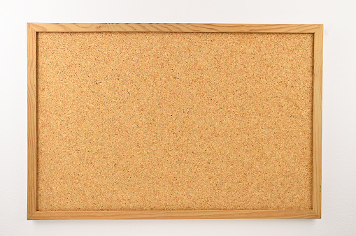 Cork board with a wooden frame against a white background